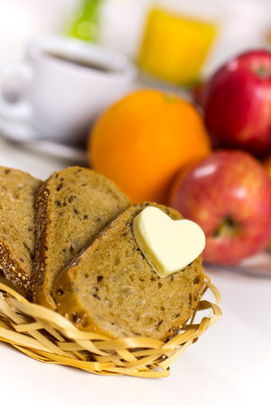Slices of bread in the basket of butter in a heart   A healthy breakfast  Coffee, juice and fresh fruit の写真素材