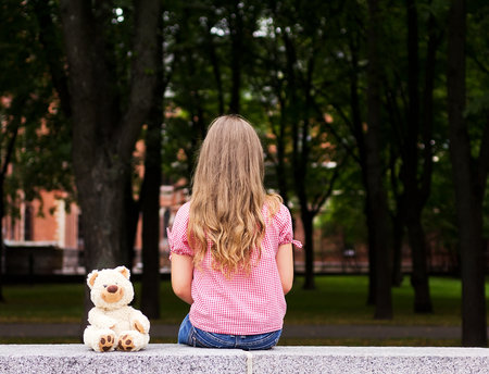 A little girl sitting in the park, visible only in the back の写真素材