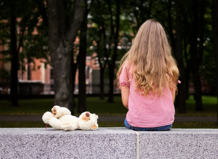 A little girl sitting in the park, visible only in the back.の写真素材