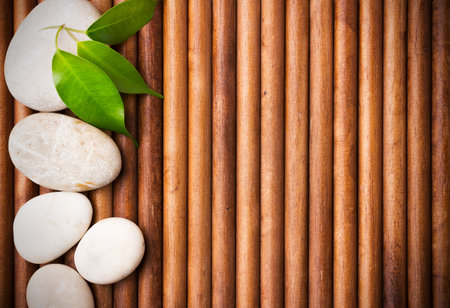 Massage stones with green leaves, wood background.の写真素材