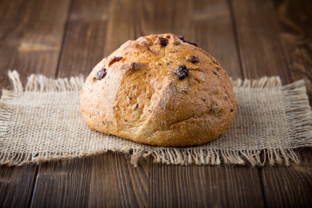 Fresh bread with cranberries on a wooden background.