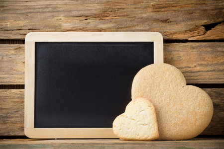Blackboard on wooden background with heart from the cookie.の写真素材