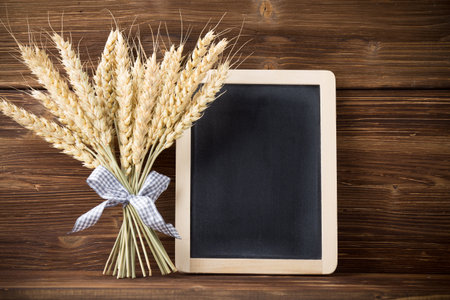 Wheat bunch with a blue ribbon, menu board, wooden background.の写真素材
