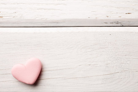 Pink heart-shaped candy on a wooden background.の写真素材