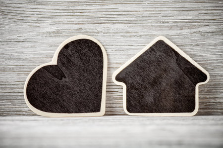 Board in the form of home on a white wooden background.の写真素材