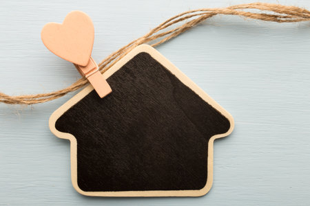 Pinned to the board with home-shaped pegs on a wooden background.の写真素材