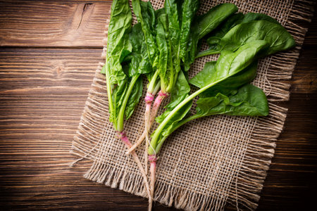 Spinach with roots on the wooden background.