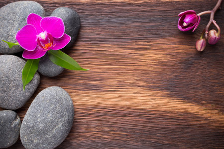 Orchid flower on wooden background with spa stones.の写真素材