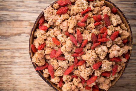 Muesli with goji berries in a bowl on a wooden background.の写真素材