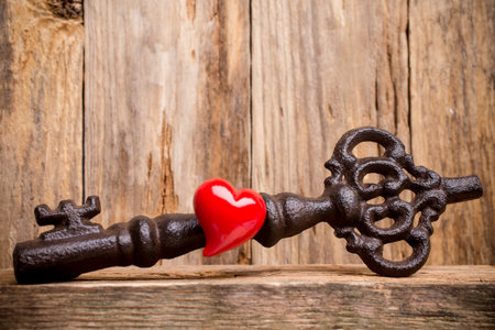 Old vintage key with heart on wooden background.の写真素材