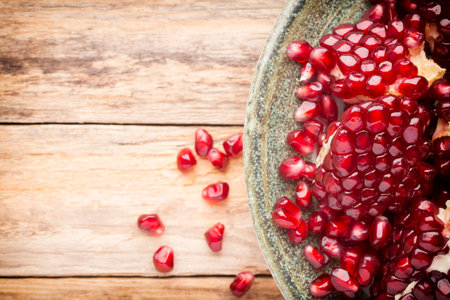Pomegranate particles on a green plate and wooden table.の写真素材
