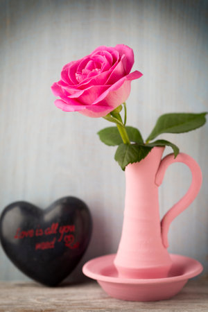 Pink roses in a vase with a Valentine\'s Day decoration on a wooden shelf.の写真素材