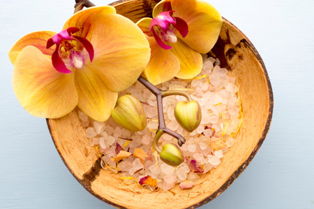 Sea salt in a bowl on a wooden table, yellow orchid.の写真素材