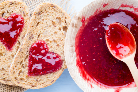 Grain slice of bread with jam heart shape.の写真素材