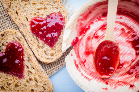 Grain slice of bread with jam heart shape.の写真素材