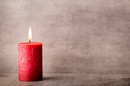 Red burning candle on a gray background. Interior items.の写真素材
