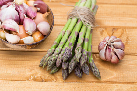 Banches of fresh green asparagus, garlic, on wooden background, top viewの写真素材