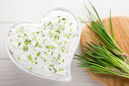 Bowl of cream cheese with green onions, dip sauce on wooden table.の写真素材