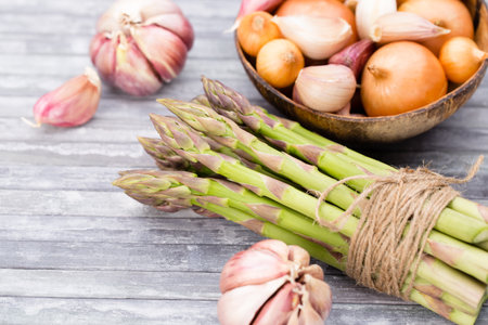Banches of fresh green asparagus, garlic, on wooden background, top viewの写真素材