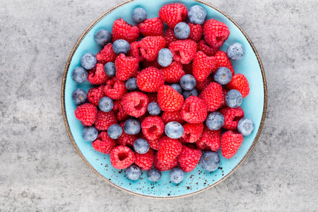Fresh berries in a plate on a  wooden background. Flat lay, top view, copy space.