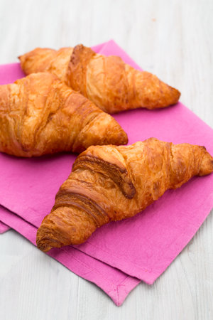 Tasty buttery croissants on old wooden table.の写真素材