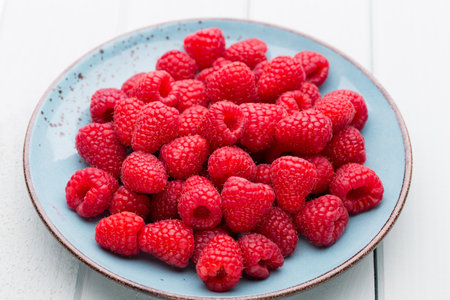 Fresh berries in a plate on a  wooden background. Flat lay, top view, copy space.