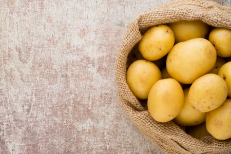 Sack of fresh raw potatoes on wooden background, top view.の写真素材