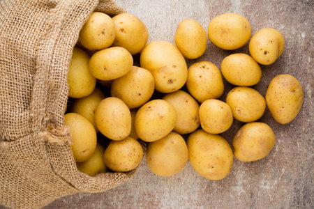 Sack of fresh raw potatoes on wooden background, top view.の写真素材
