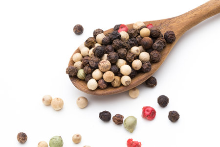 Pepper seed on spoon on white background.