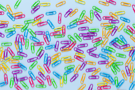 Color paper clips on blue background, copy space. Top view, flat lay. Back to school, college,...