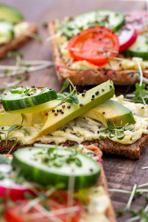 Variety of mini sandwiches with cream cheese, vegetables and salami. Sandwiches with cucumber, radish, tomatoes, salami on a gray background, top view. Flat lay.の写真素材