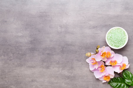 Spa aromatherapy flat lay of various beauty care products decorated with simple orchid flowers.