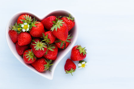 Strawberry heart. Fresh strawberries in plate on white wooden table. Top view, copy space.の写真素材