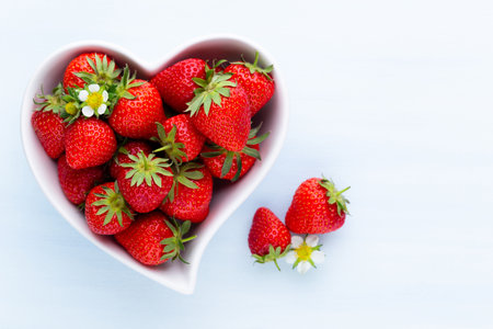 Strawberry heart. Fresh strawberries in plate on white wooden table. Top view, copy space.の写真素材