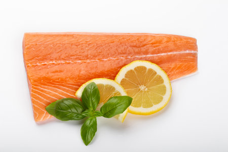Slice of red fish salmon with lemon, basil isolated on white background. Top view. Flat layの写真素材