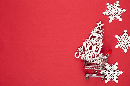 Shopping cart with christmas tree on red table.の写真素材