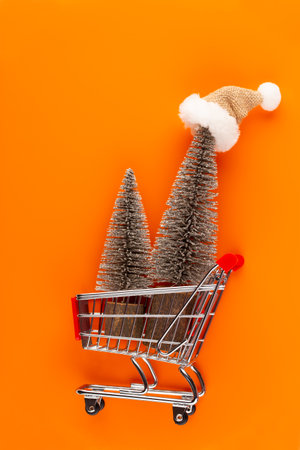 Shopping cart with christmas tree on red table.の写真素材