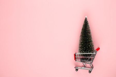 Shopping cart with christmas tree on red table.の写真素材