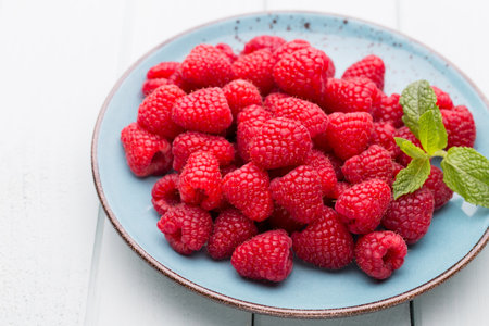 Fresh berries in a plate on a  wooden background. Flat lay, top view, copy space.の写真素材