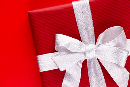 Top view of arranged wrapped christmas gift boxes with ribbons on red tabletop.の写真素材