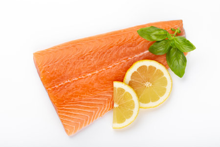 Slice of red fish salmon with lemon, basil isolated on white background. Top view. Flat layの写真素材