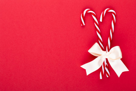 Christmas candy canes, stick and decor on color background. Sweet Christmas Card - Candy Canes With Ribbon - Image.の写真素材