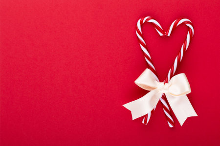 Christmas candy canes, stick and decor on color background. Sweet Christmas Card - Candy Canes With Ribbon - Image.の写真素材