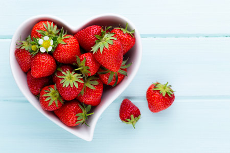 Strawberry heart. Fresh strawberries in plate on white wooden table. Top view, copy space. の写真素材
