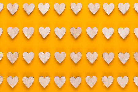 Small wooden hearts on a yellow background. A creative idea. Valentine day greeting card.の写真素材