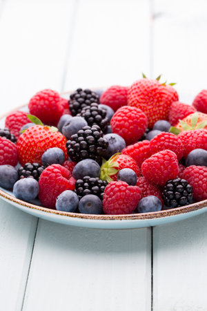 Fresh berries salad in a plate on a wooden background. Flat lay, top view, copy space.の写真素材
