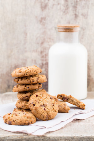 Chocolate oatmeal chip cookies with milk on the rustic wooden table.の写真素材