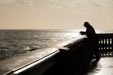 silhouette of fisherman waiting his fish while the sun goes downの写真素材