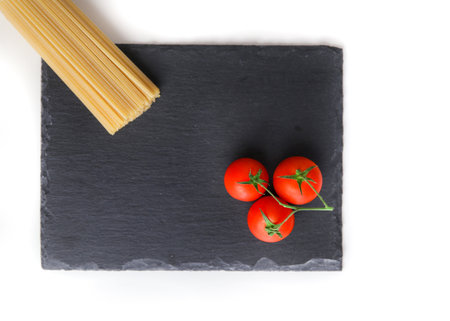Uncooked spaghetti and tomatoの写真素材