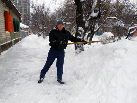 A man with a shovel clears snow from the road.の写真素材